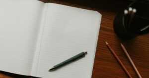 Quaderno aperto con penna e matite sulla scrivania