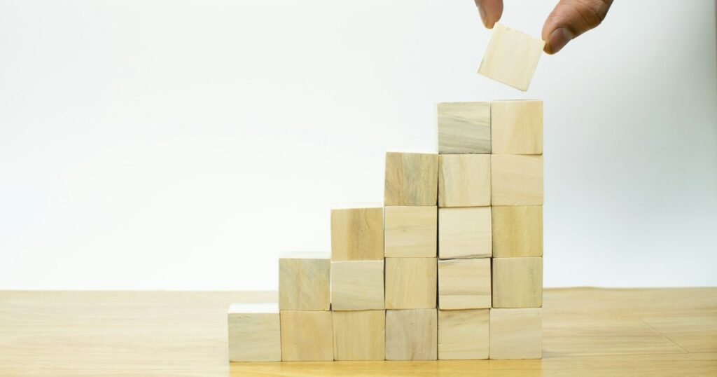Una mano posa un cubo di legno in cima a una piramide di blocchi