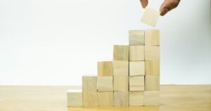 Una mano posa un cubo di legno in cima a una piramide di blocchi